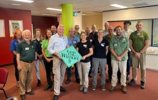 A group of environmentalists holding a blue sign with the text Land for Wildlife